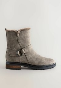 Grau Wildleder-Ankle-Boot mit Kunstfellbesatz, dekorativem Riemen und Metallring, gummierter Sohle mit Profil und hölzernem Akzent an der Ferse.