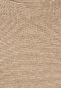 Ljust beige stickad tyg med en strukturerad yta, som har ett subtilt mönster och jämn sömnad genom hela tyget. Slät vid beröring.