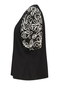 Top noir avec un corps uni et une manche bouffante brodée blanche texturée ornée de motifs abstraits.