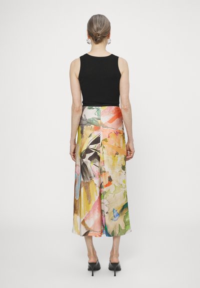 Top noir sans manches associé à une jupe maxi fluide à fleurs multicolores, présentant des motifs contrastés et une texture douce.