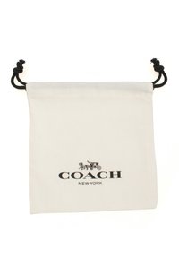 Vit bomullspåse med dragsnöre, med svart logotext "COACH NEW YORK" och en bild av en hästdragen vagn. Texturerad yta, enkelt design.