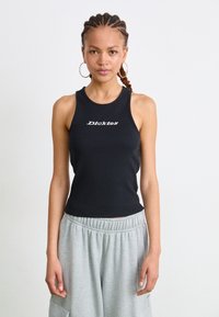 Svart ribbestrikket tanktopp med hvit "Dickies" tekstlogo, kombinert med grå joggebukser med elastisk liv og lommer.