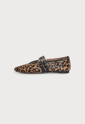 Chaussure plate à bout pointu avec imprimé léopard, lanières en cuir noir et détails de boucle argentée sur fond blanc.