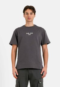 Grijze katoenen T-shirt met korte mouwen en een ronde halslijn. Bevat witte bedrukt tekst "Sixth June Paris" op de borst.