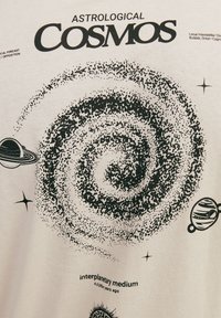 T-shirt blanc avec un design graphique noir représentant une galaxie spirale, des planètes et des étoiles. Comprend le texte "Cosmos Astrologique" et des détails sur l'espace.