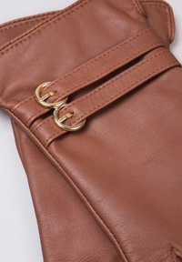 Brown leather gloves with two gold circular buckles and stitched detailing on the wrist area. Smooth texture, fingerless design.