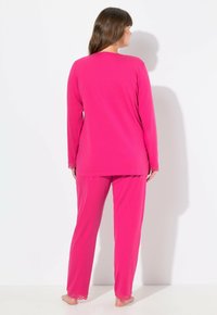 Zweiteiliges Schlafanzug-Set in kräftigem Pink. Langärmliges Oberteil mit rundem Ausschnitt; Hose mit elastischem Bund und Spitzenabschluss an den Bündchen. Weiche Stofftextur.