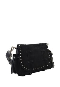 Sac à épaule en daim noir avec des clous en argent soulignant le rabat, une bandoulière à motif réglable et un fermoir en métal sur fond blanc.