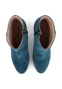 Ein Paar türkisfarbene Wildleder-Stiefeletten mit Seitenreißverschlüssen und beige gefüttertem Innenleben, von oben auf einem weißen Hintergrund betrachtet.