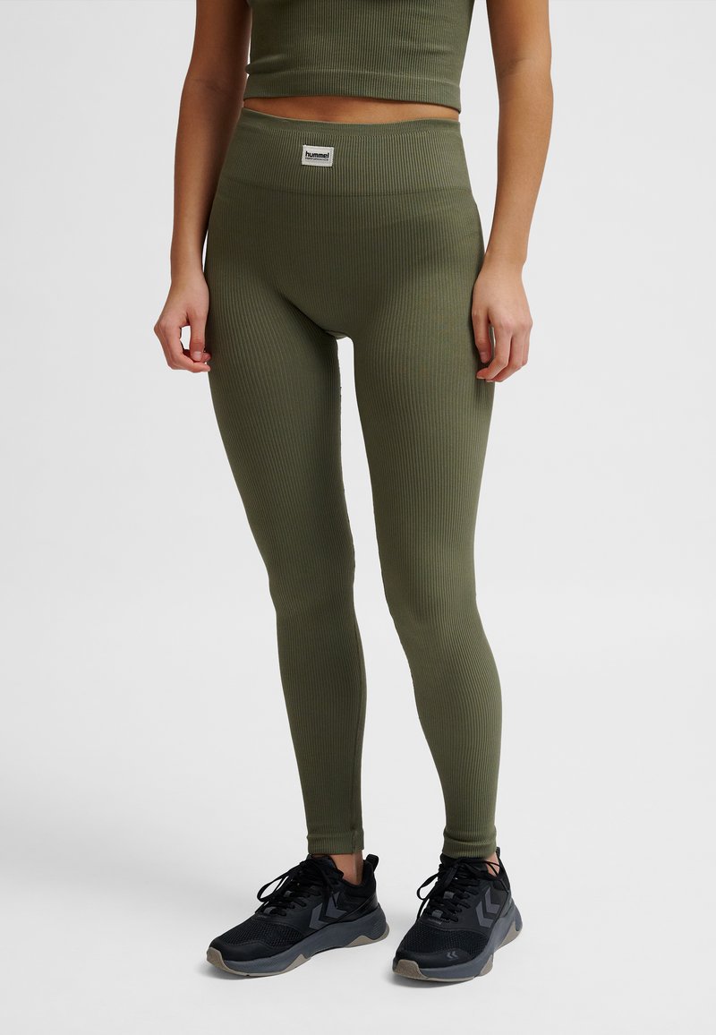 Olivgröna ribbade leggings med hög midja och en liten märkesetikett. Stylist med svarta sportskor.