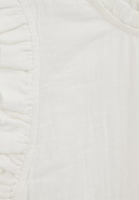 White fabric with a subtle texture, featuring a ruffled edge along a seam. The ruffle has a continuous, delicate design.