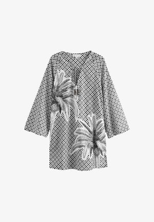 Tunica alb-negru cu un model geometric ce include grafica palmierilor și ananasului; decolteu în V și mâneci 3/4.