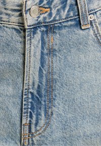 Light blue denim jeans feature contrasting orange stitching, a metal button at the waistband, and a smooth texture with a slightly faded finish.