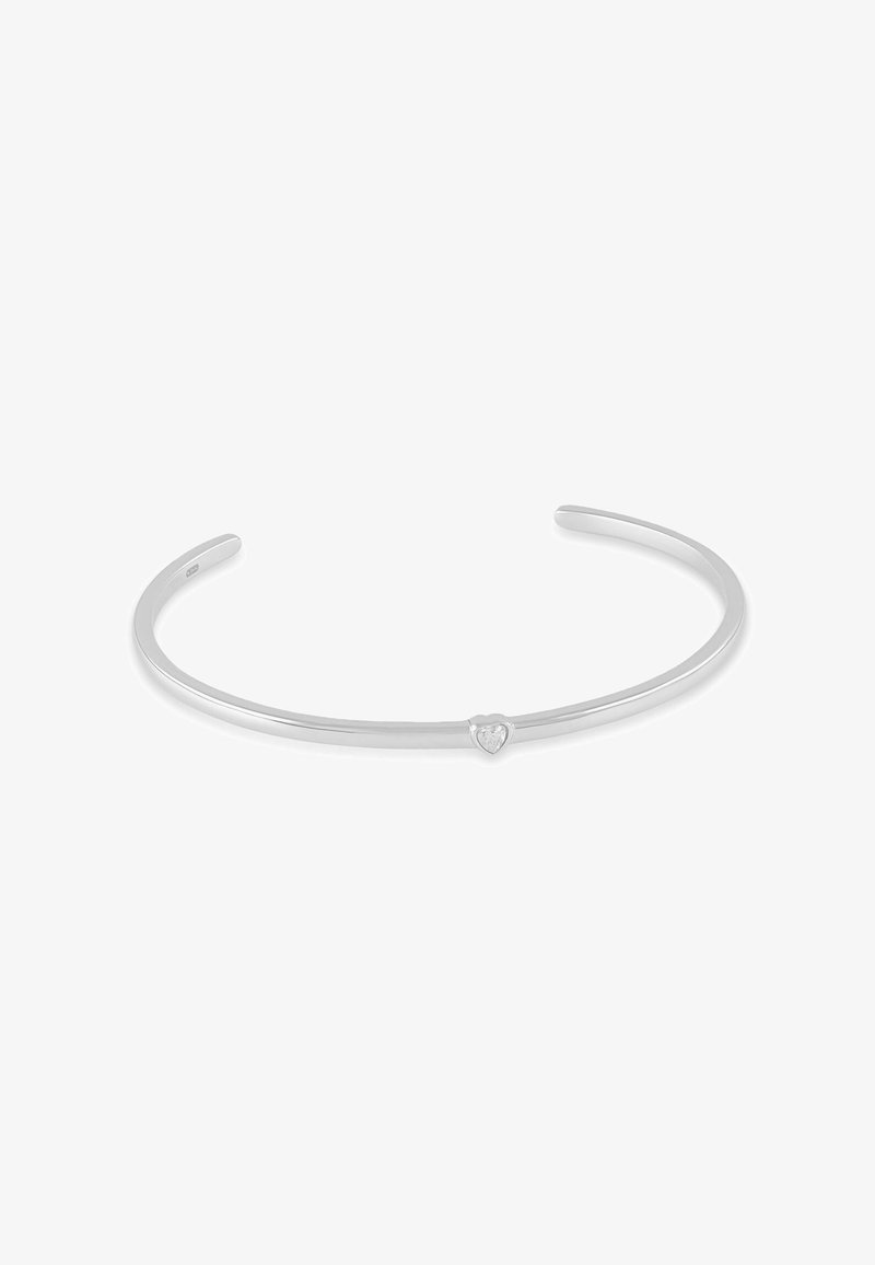 Bracelet manchette mince en argent avec une petite pierre en forme de cœur centrée sur le bracelet, ouvert aux extrémités pour un ajustement réglable.