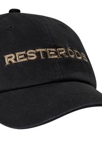 Sort baseball cap med en buet skygge, prydet med "RESTERÖDS" broderet i metalisk guldtråd på forsiden. Stofstrukturen er glat.