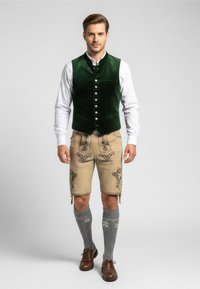 Groene fluwelen vest met zilveren knopen, witte blouse, beige leren shorts met borduursel, gecombineerd met grijze kniekousen en bruine schoenen.