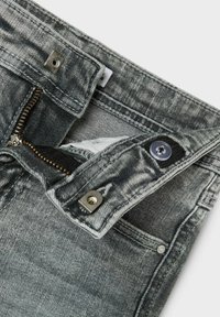 Jeans de mezclilla gris con un acabado descolorido. Incluye una cremallera, cierre de botón y herrajes metálicos. Tiene un pequeño bolsillo interior.