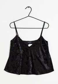 Svart sammetslinne med tunna justerbara band, V-ringning och utsvängd nederdel. Slät textur med lätt glans och etikett synlig inuti.