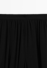 Schwarzer, plissierter Stoffbund mit glatter Textur. Verfügt über ein elastisches Band für Dehnbarkeit und Komfort, entworfen für einfaches Anziehen.