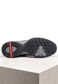 Černá podrážka sportovní obuvi má šestihranný vzor běhounu, šedou mezipodešev a červený proužek jako akcent pro lepší přilnavost a stabilitu.