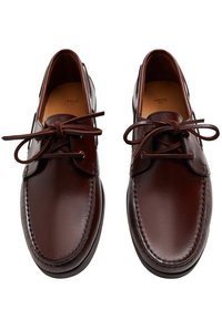 Chaussures en cuir marron à bout arrondi, modèle à lacets avec des coutures décoratives le long des bords. Texture lisse, style minimaliste.