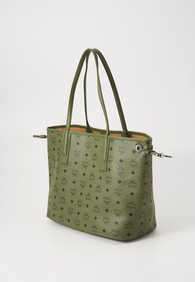 Green textured leather tote bag with black MCM logo pattern and double shoulder straps on a white background.