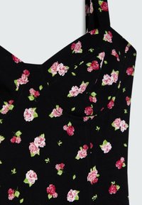 Robe en tissu noir ornée de petits motifs floraux roses et blancs, avec un corsage ajusté et des bretelles réglables.