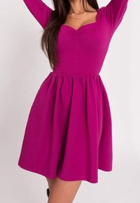 Robe fuchsia à manches longues avec un corsage ajusté, un décolleté carré et une jupe froncée. Fabriquée en matière extensible pour plus de confort.