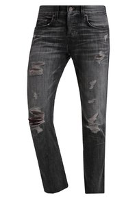 Jeans de mezclilla negros con corte slim, presentando áreas desgastadas y desgarros deshilachados en el frente, cinco bolsillos y cierre de botón.