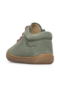 Zelené semišové boty pro batolata s hnědou šňůrkou, nízkým designem kolem kotníku, gumovou podrážkou a texturovanými detaily na spodní straně. Obsahuje logo na boku.