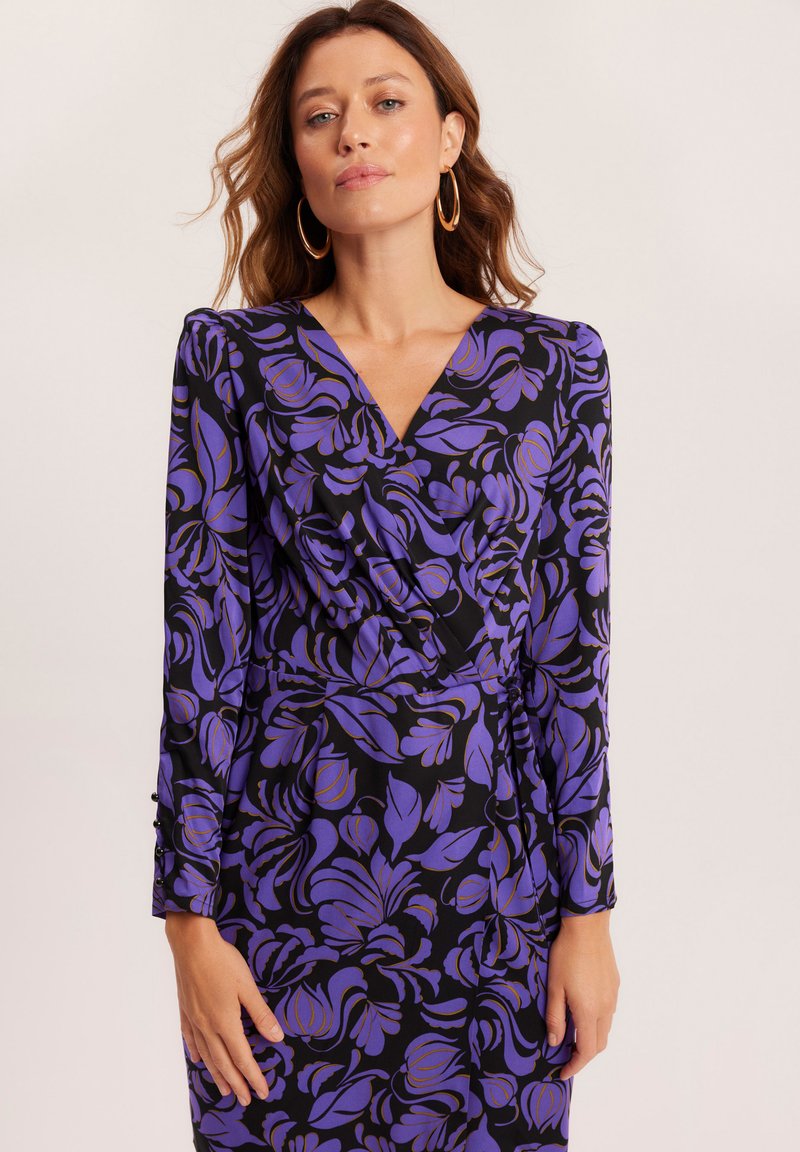 Sukienka z długim rękawem z głębokim dekoltem w kształcie litery V, czarna tkanina z fioletowym kwiatowym wzorem oraz subtelnymi detalami na mankietach.