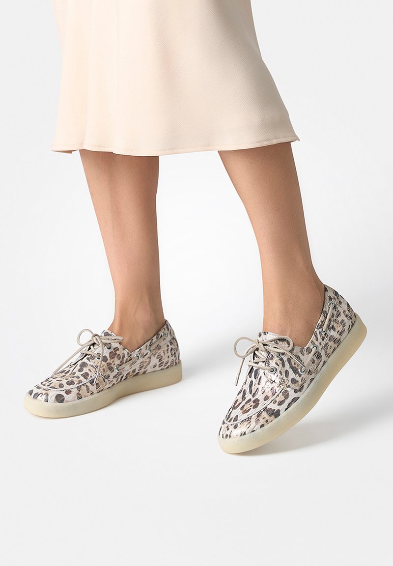 Buty sportowe w cętki lamparta z sznurowanym fasonem, teksturowaną cholewką i jasnokolorową gumową podeszwą. Buty mają zaokrąglony nosek i subtelne akcenty.