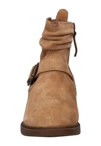 Tan suède enkellaars met een slouch-design, een zijrits en een decoratieve gespaccent op de band. Platte rubberen zool.