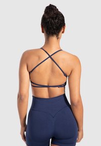 Sujetador deportivo azul marino con tirantes ajustables en forma de cruz. Tejido texturizado con un diseño posterior elegante y un detalle de cierre con gancho.