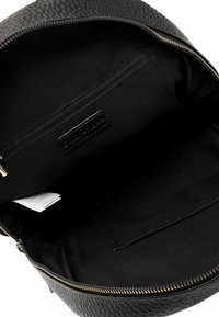 Zaino in pelle nera con esterno texturizzato, zip dorata e interno in tessuto nero; include una tasca con zip e una tasca aperta.