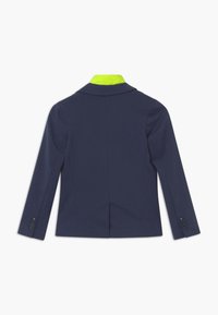 Marineblazer mit einem leuchtend grünen Kragen, tailliertem Design, zwei Knopfverschluss und langen Ärmeln mit Knopfakzenten. Glatte Textur.