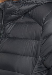 Sort dunjakke med quiltet design, glat tekstur og lynlåslukning. Hættetrøje med diagonale og horisontale syningsdetaljer.