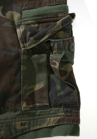 Kamufliažinės cargo šortai tamsiai žalios ir rudos spalvos, su priekinė kišene, užsegimu ant sagos ir minkštu audiniu. Akcentai – kontrastingos medžiagos elementai.