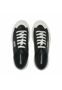 Baskets en toile noires avec lacets blancs, semelles en caoutchouc texturées et étiquette de logo. Présentent un design basse et un bout arrondi.