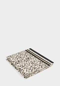 Coperta con stampa leopardata in crema e nero, con bordo a strisce nero e crema. Texture morbida, piegata ordinatamente per l'esposizione.