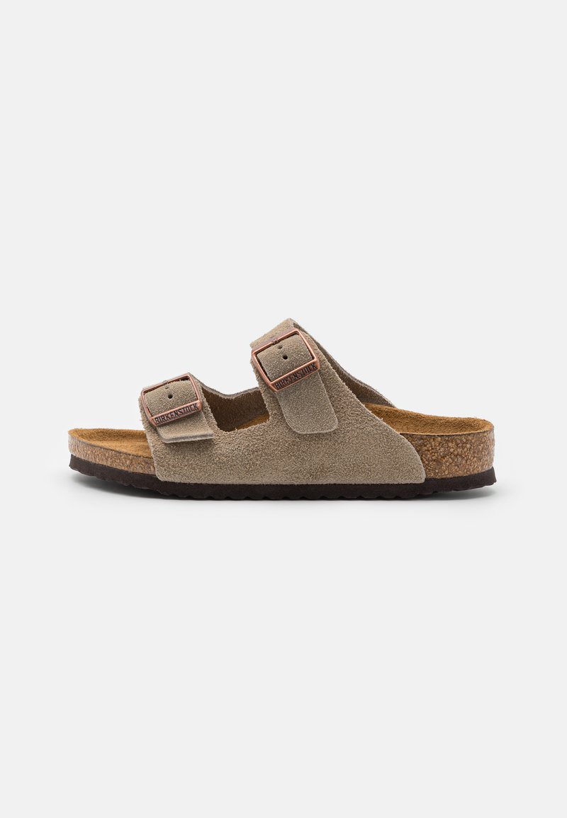 Sandal com duas tiras em camurça de cor castanha clara, com fivelas ajustáveis. Palmilha de cortiça e sola de borracha texturizada para aderência. Design casual.