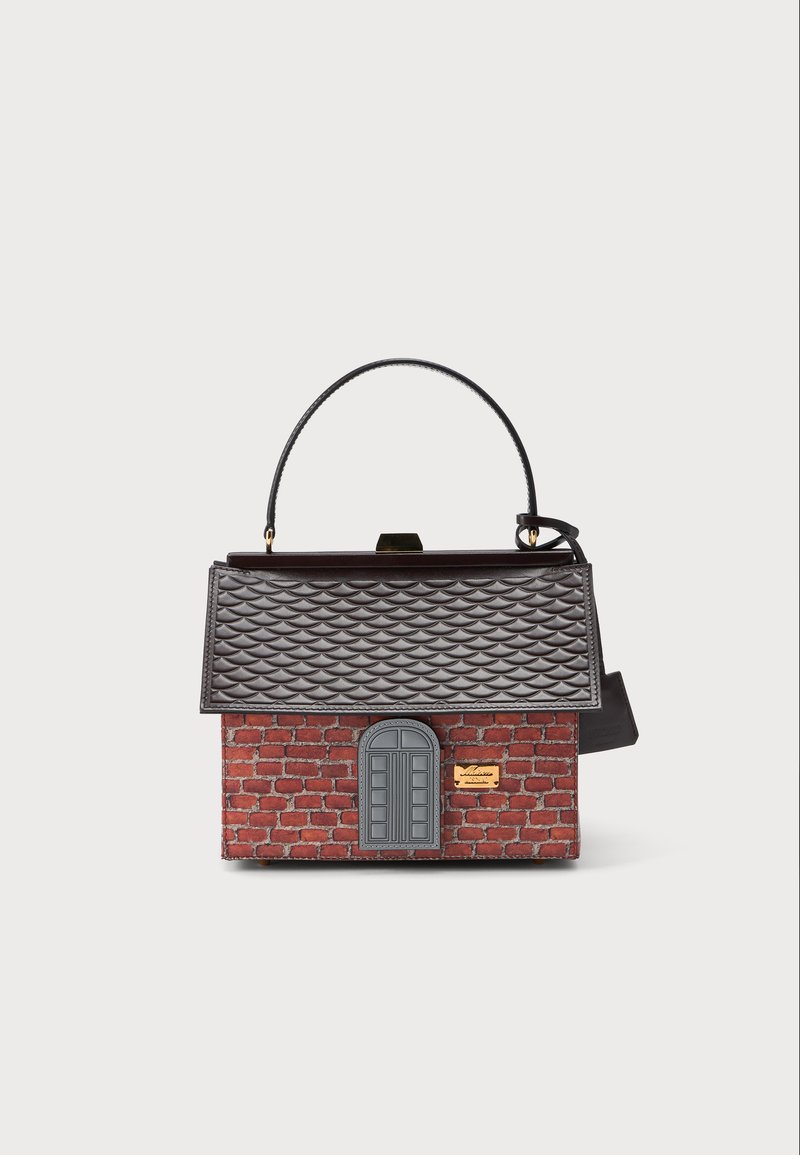 Sac à main conçu comme une petite maison avec un motif en briques rouges, un détail de fenêtre cintrée grise et un rabat texturé en forme de toit gris foncé.