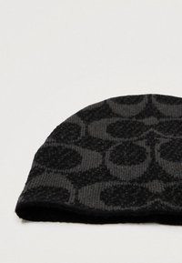 Berretto lavorato a maglia nero con una texture liscia, caratterizzato da un motivo geometrico di cerchi interconnessi in tonalità più scure, bordo piegato.