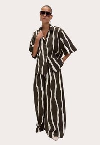 Brun- og hvidstribet oversize skjorte og bukser med vide ben, med korte ærmer, krave og knapper foran.