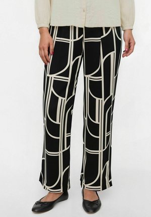 Pantaloni neri a gamba larga con un motivo geometrico beige, caratterizzati da una superficie tessile liscia e una vestibilità comoda. Abbinati a scarpe nere basse.