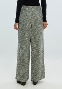 Weite Hosen aus strukturiertem Schwarz-Weiß-Strick. Mit hoher Taille und einem fließenden Design, das bis zum Boden reicht.