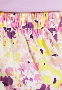 Kukkamekko, jossa on kootun elastisen vyötärönauhan. Esittelee pastelliväripaletin, jossa on vaaleanpunaista, keltaista ja liilaa vesiväri-kuvioinnilla.