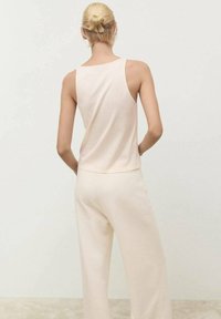 Helle beige Trägershirt und passende weit geschnittene Hose, aus einem weichen Material gefertigt. Besitzt ein einfaches, lockeres Design ohne sichtbare Muster.