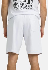Shorts atletici bianchi con un design elegante, vita elastica e una tasca posteriore per maggiore praticità. Tessuto dalla consistenza liscia.