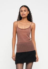 Brun ribbet strikket tank topp med tynne stropper, med en teksturert nederdel, kombinert med et svart, lodden mini skjørt. Glatt stoffer finish.